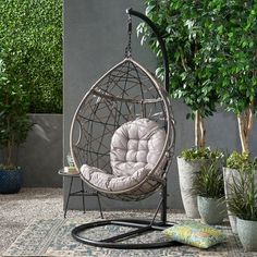 a hanging egg chair in front of a potted plant