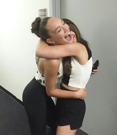 two young women hugging each other in front of a mirror