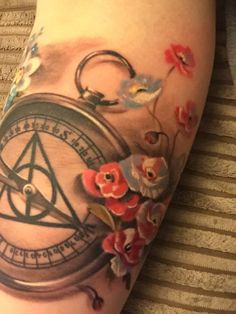 a tattoo with flowers and a compass on it