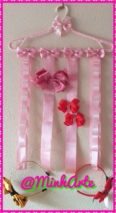 a pink and white striped wall hanging with bows on it's hanger next to scissors