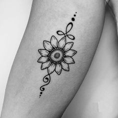 a black and white photo of a woman's thigh with a sunflower tattoo on it