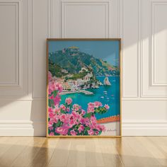 an art print with pink flowers in front of a white wall and wooden flooring