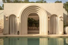 an outdoor swimming pool with white walls and arches