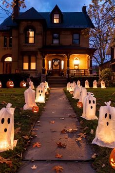 halloween decorations in front of a house with pumpkins and ghost bags on the lawn