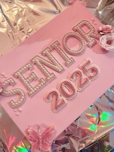 a pink sign that says senior 2055 with flowers and ribbons on it in front of tin foil