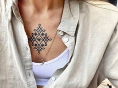 a woman with a cross tattoo on her chest is looking at the camera while wearing a white shirt