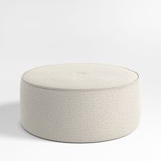 an upholstered round ottoman on a white background with no people around it,