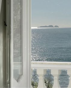 an open window looking out at the ocean and land in the distance from a balcony