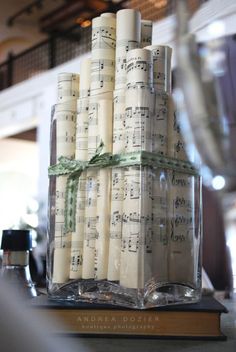 a stack of candles sitting on top of a table covered in sheet music notes and green ribbon