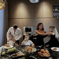 a woman and two children are sitting at a table with food