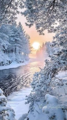 the sun is setting over a river surrounded by snow covered trees