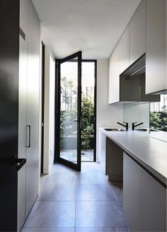 an empty kitchen with white cabinets and black glass doors on the side walk leading to a patio