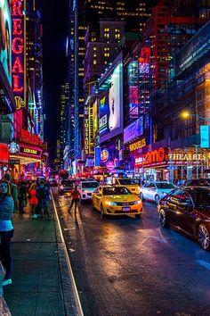 a busy city street at night with neon signs and cars on the road, people walking down the sidewalk