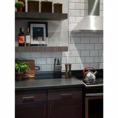 a stove top oven sitting inside of a kitchen next to a wooden shelf filled with utensils