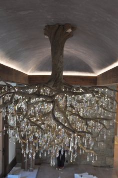 a chandelier hanging from the ceiling in front of a tree with crystal drops