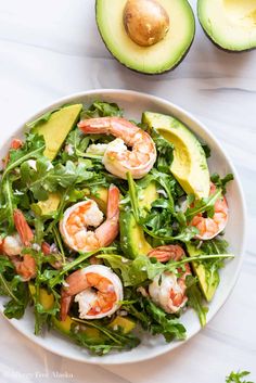 a salad with shrimp, avocado and lettuce on a white plate