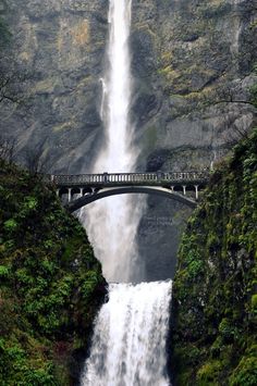 a large waterfall with a bridge over it