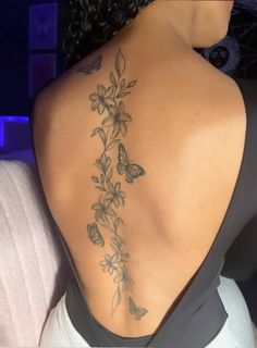 the back of a woman's neck with flowers and butterflies on her lower back