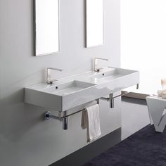 two white sinks sitting next to each other in a bathroom with mirrors on the wall