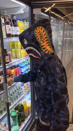 a person wearing a shark costume standing in front of a refrigerator filled with drinks and beverages