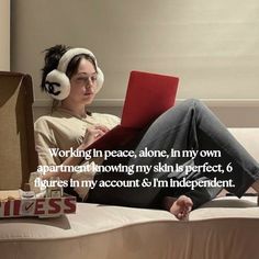 a woman with headphones sitting on a bed using a laptop