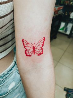 a red butterfly tattoo on the arm