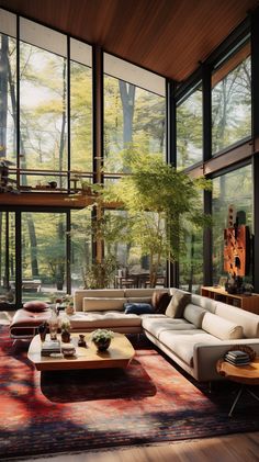 a living room filled with lots of furniture and large windows overlooking the trees in the forest