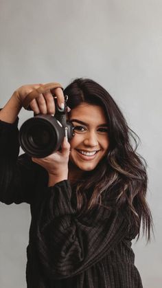 a woman is holding up a camera to take a selfie with her smile on her face