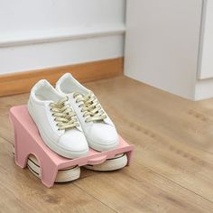 a pair of white and pink shoes sitting on top of a wooden floor