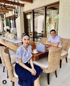 a man and woman sitting at a table in front of an open patio area with wicker chairs