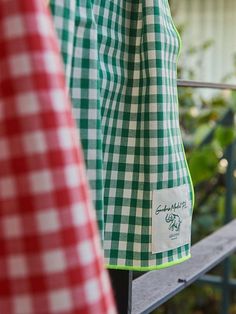 two green and white checkered shirts hanging on a rail