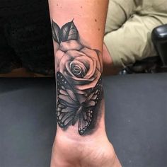 a woman's wrist with a rose and butterfly tattoo on her left arm, which is black and white