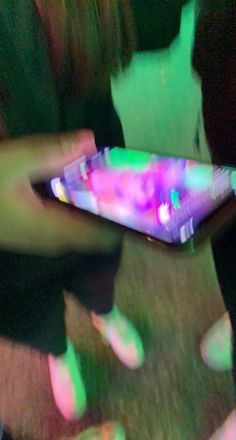 a blurry photo of someone holding a cell phone in their hand with the screen lit up