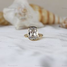 a close up of a ring on a bed with shells and seashells in the background