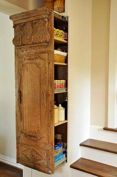 an old wooden cabinet sitting in the corner of a room next to some wood stairs