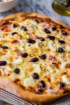 a pizza sitting on top of a metal pan covered in cheese and black olives