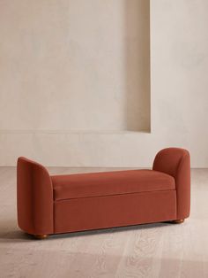 an orange couch sitting on top of a hard wood floor next to a white wall