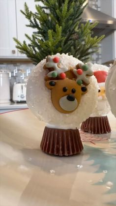 there are some christmas decorations on the table in front of a small fir tree, which is decorated with frosting and reindeer heads