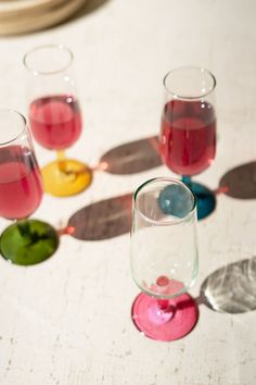 four glasses filled with liquid sitting on top of a table