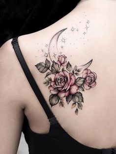 a woman's back with roses and a crescent tattoo