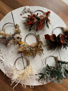 several different types of flowers are arranged on a white circular table with wood planks