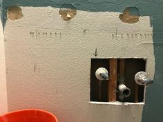 a red bucket is sitting in front of a wall with holes and screws on it