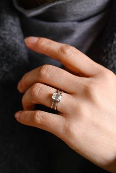 a woman's hand with two rings on her left and the other one is wearing a sweater