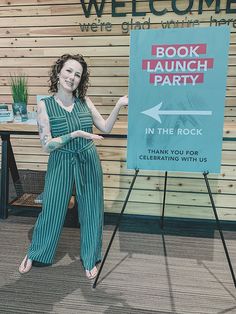 a woman standing in front of a book launch party sign