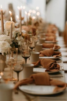 a long table is set with candles, plates and napkins for an elegant dinner