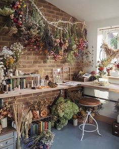 a brick wall covered in flowers and greenery next to a bar with stools