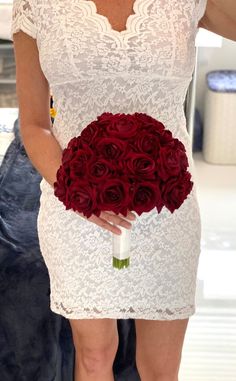 a woman holding a bouquet of red roses