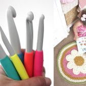 there are several crocheted utensils in the hand and on the floor