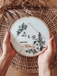 two hands holding up a embroidery hoop with the word b & r on it and flowers