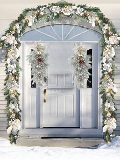 a white door decorated with christmas wreaths and lights